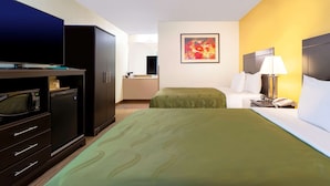 A hotel room with a bed, a desk with a lamp, a TV, and a microwave. - Quality Inn at Arlington Highlands (Arlington)
