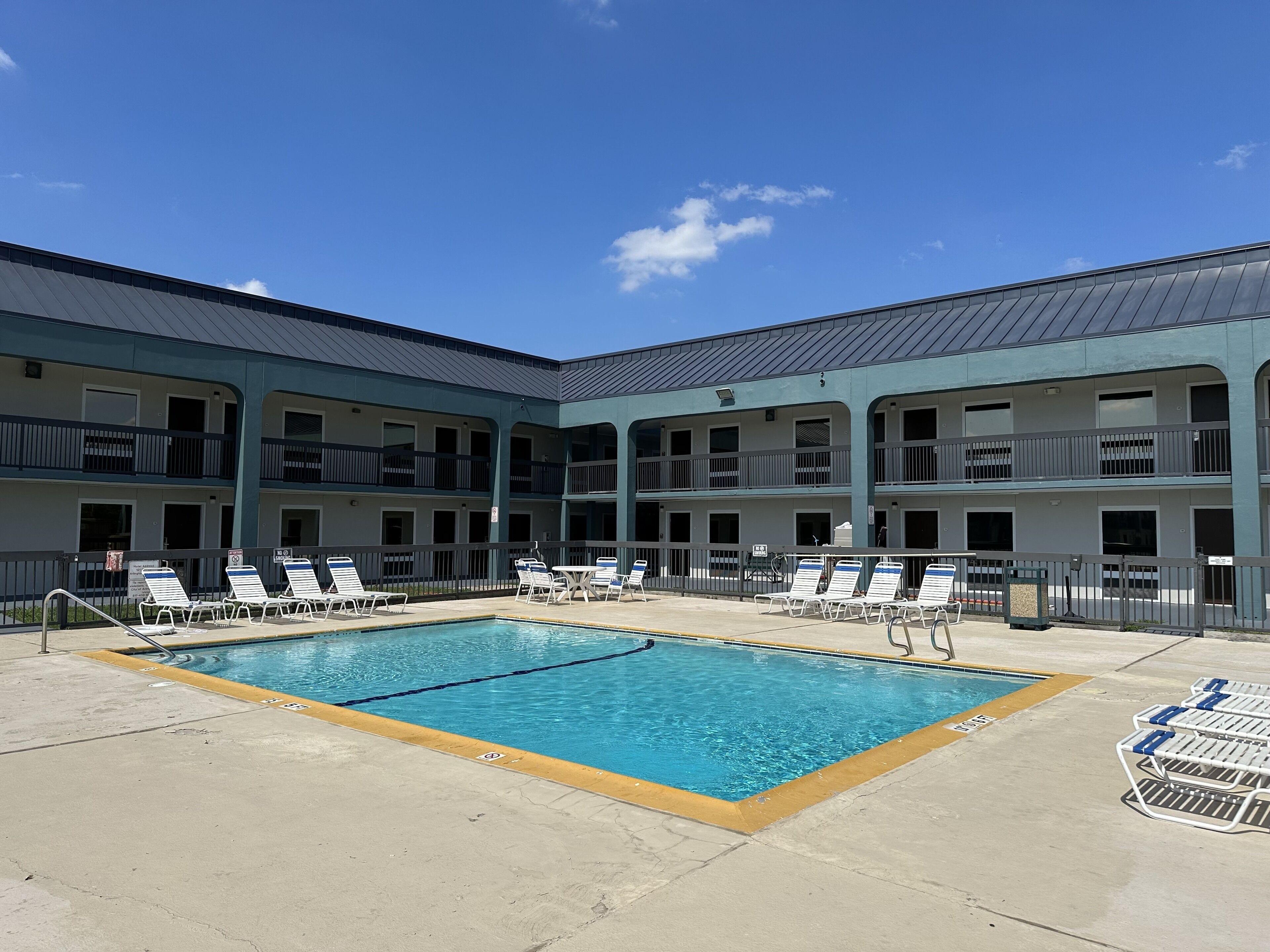 A pool area with lounge chairs and a building with multiple balconies.