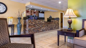 A lobby with a reception desk, patterned chairs, a clock, and a decorative vase. - Quality Inn at Arlington Highlands (Arlington)