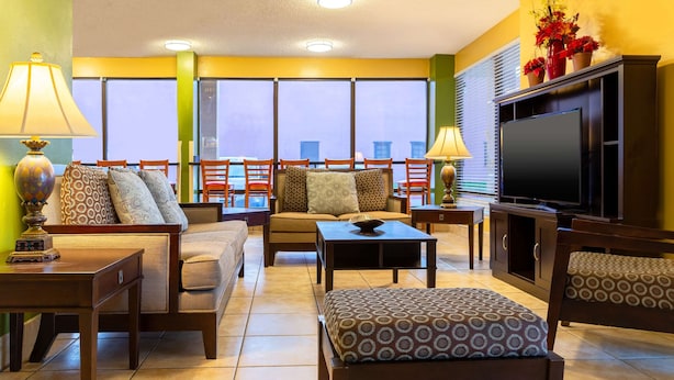 A living room with a sofa, chairs, a coffee table, a TV, and a balcony with a view. - Quality Inn at Arlington Highlands (Arlington)