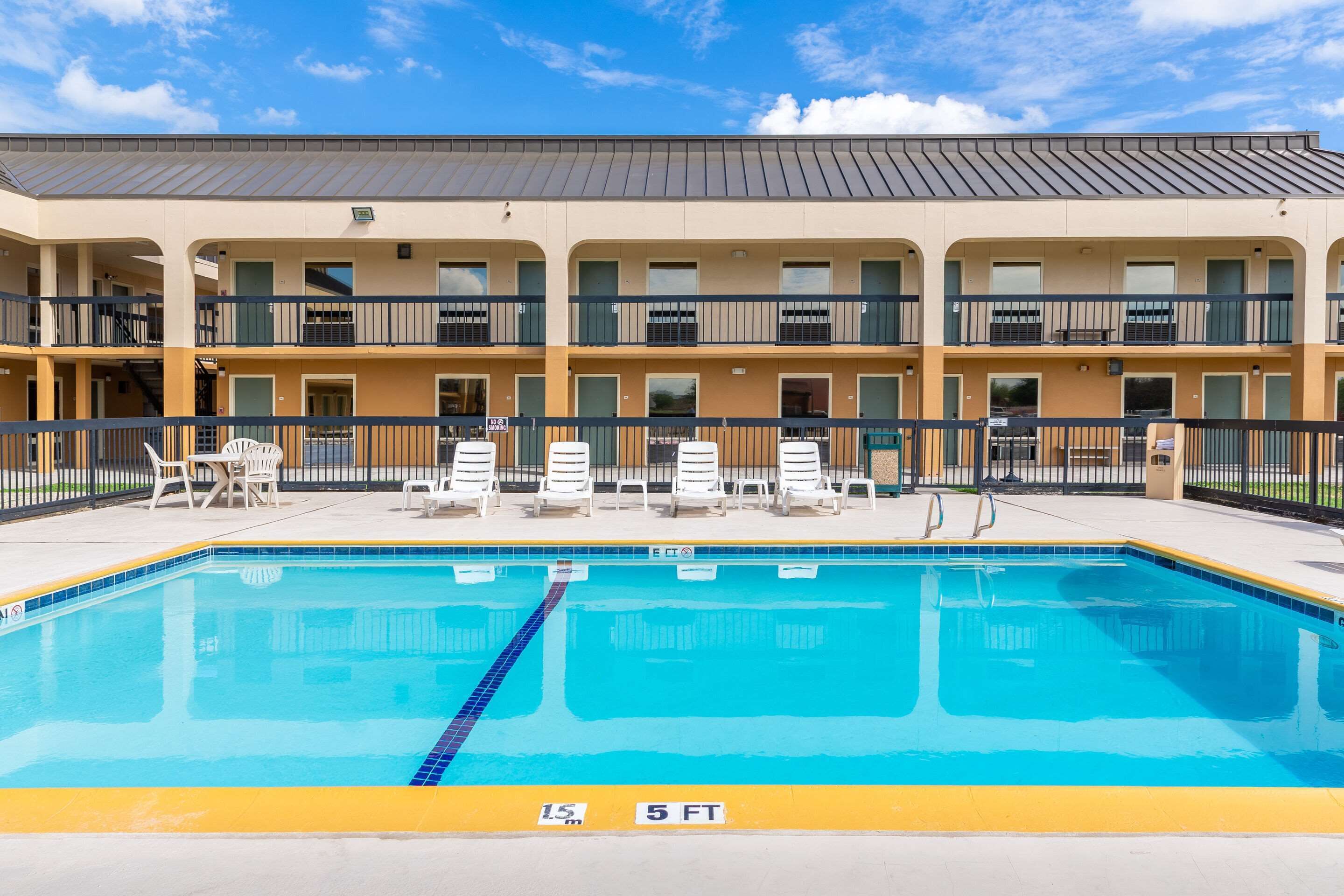 A hotel with a swimming pool, multiple balconies, and outdoor seating.