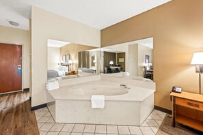 A large bathroom with a freestanding bathtub, a large mirror, and a vanity with a lamp.