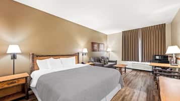 A hotel room with a large bed, a sofa, a desk, and a television.