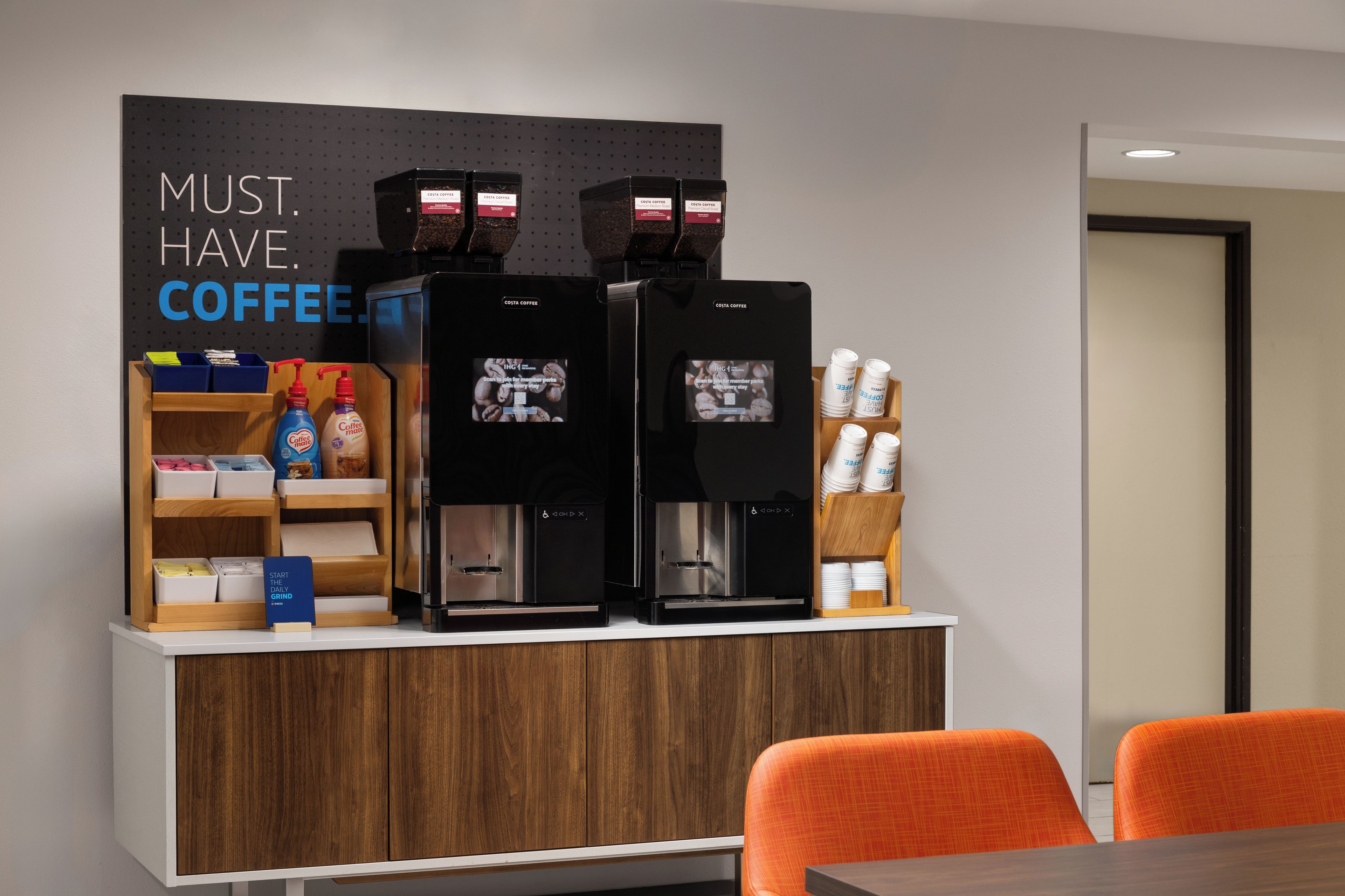 A coffee station with two espresso machines, a coffee grinder, and a sign that reads 'MUST HAVE COFFEE.'