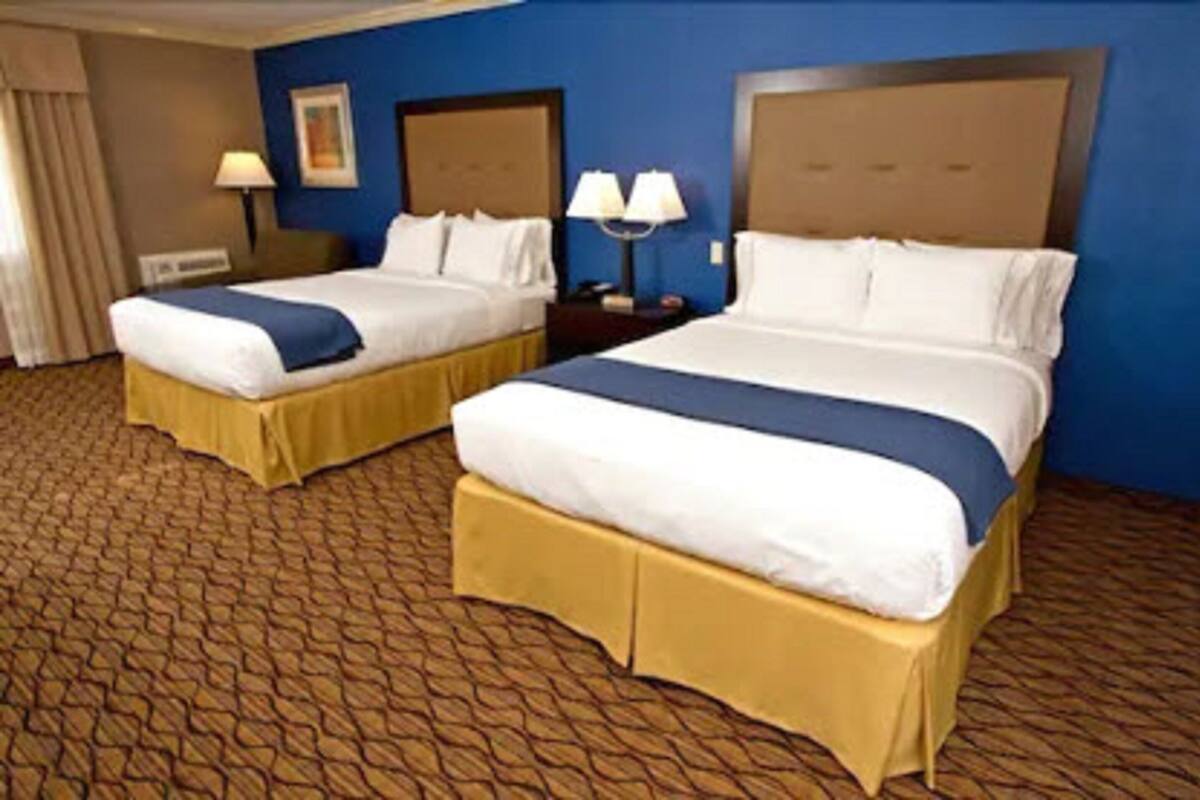 A hotel room with two beds, a blue wall, and a patterned carpet.