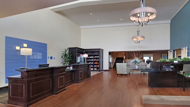 A spacious lobby with a reception desk, a seating area, and a staircase leading to an upper floor. - Holiday Inn Express Port Hueneme by IHG (Port Hueneme)