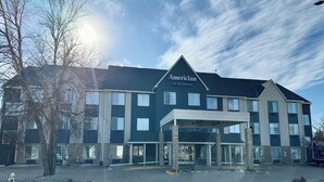 A multi-story hotel with a prominent entrance, a covered area, and a parking lot. - AmericInn by Wyndham Galesburg (Galesburg)
