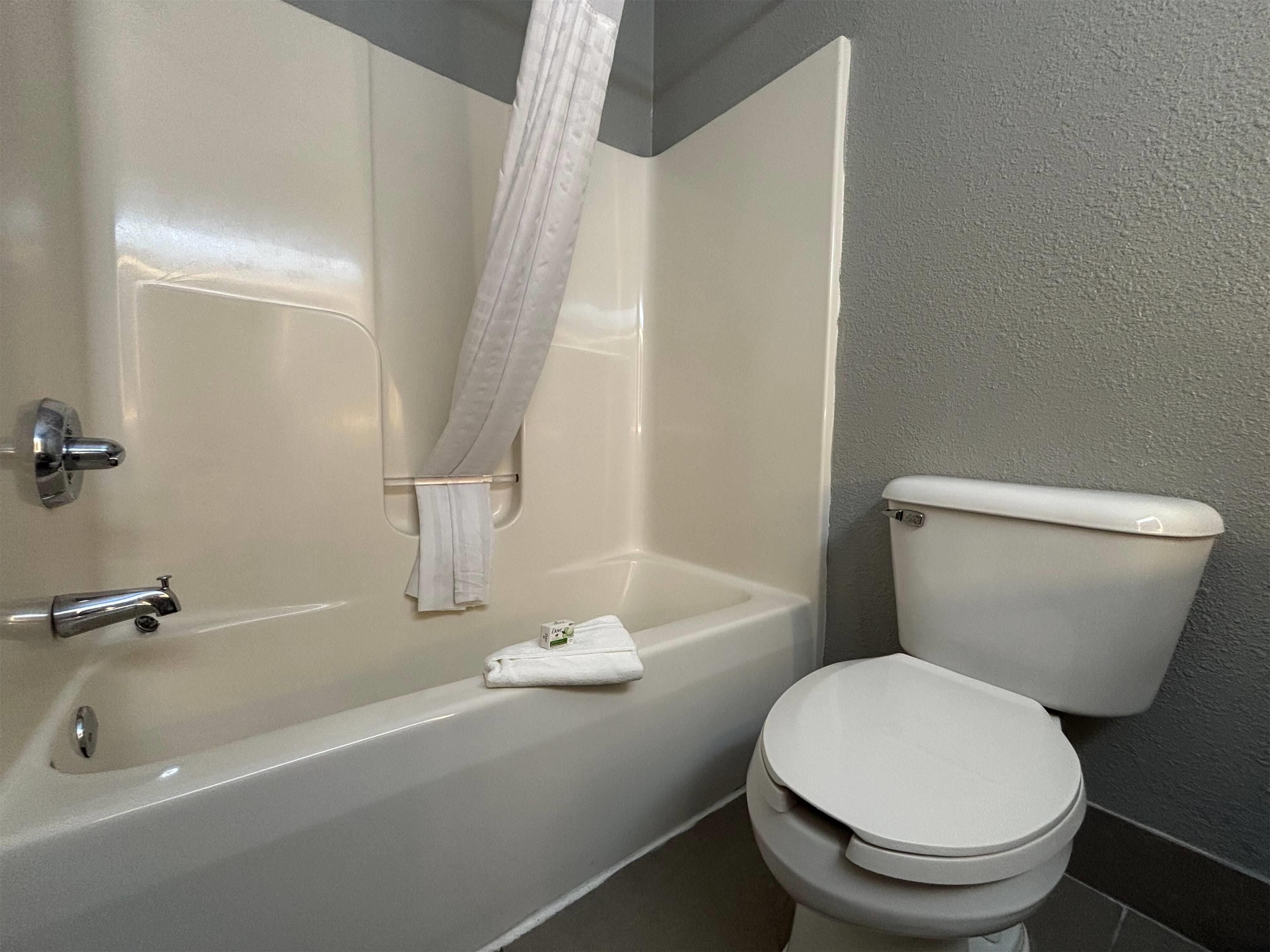 A bathroom with a bathtub, toilet, and a towel hanging on the wall.