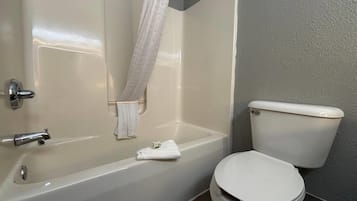 A bathroom with a bathtub, toilet, and a towel hanging on the wall.