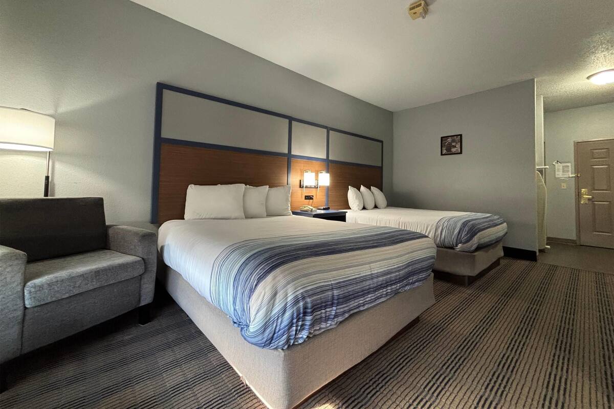 A hotel room with a large bed, two bedside tables, a chair, and a lamp.