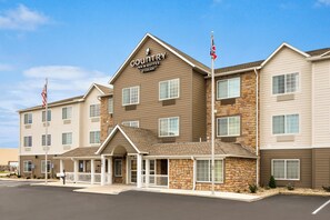A Country Inn & Suites building with a stone facade, multiple windows, and a flagpole.