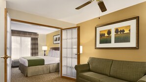 A hotel room with a bed, a green sofa, a ceiling fan, and two framed pictures on the wall. - Country Inn & Suites by Radisson, Marion, OH (Marion)