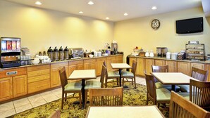 A hotel dining area with wooden furniture, a coffee machine, and a TV mounted on the wall. - Country Inn & Suites by Radisson, Marion, OH (Marion)