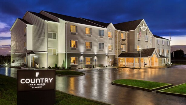 A multi-story hotel with a well-lit entrance, a signboard, and a parking lot. - Country Inn & Suites by Radisson, Marion, OH (Marion)