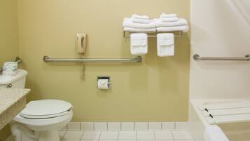 Baño con inodoro, toallero con toallas dobladas, secamanos y barra de apoyo.