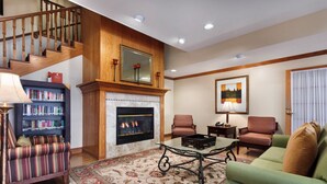 A living room with a fireplace, bookshelves, a sofa, and a staircase. - Country Inn & Suites by Radisson, Marion, OH (Marion)