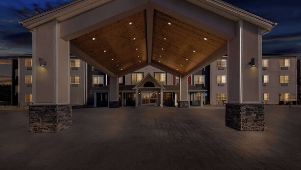 A hotel entrance with a covered lobby area, stone pillars, and multiple windows. - Best Western Worlds of Fun Inn & Suites (Kansas City)