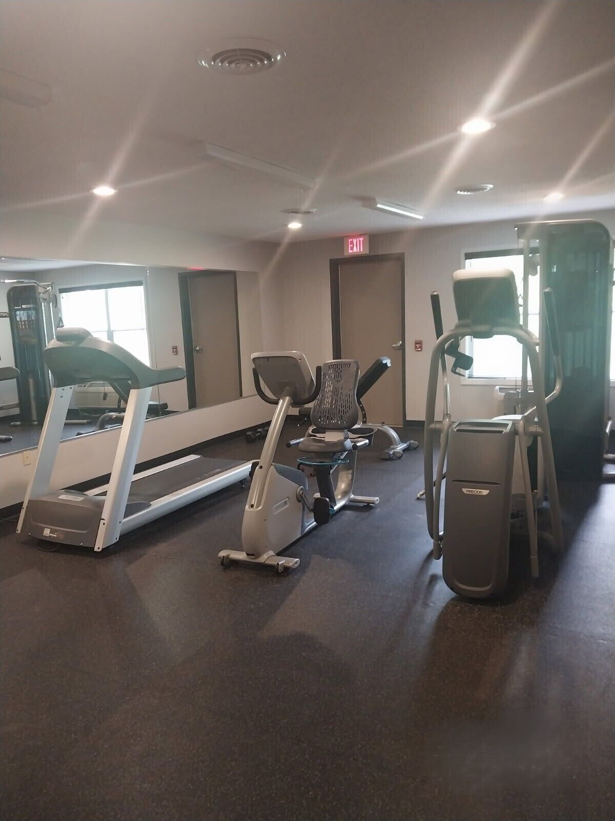 Un gimnasio con cintas de correr, elípticas y un espejo grande.