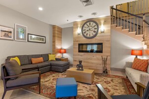 A modern living room with a sectional sofa, a coffee table, and a staircase.