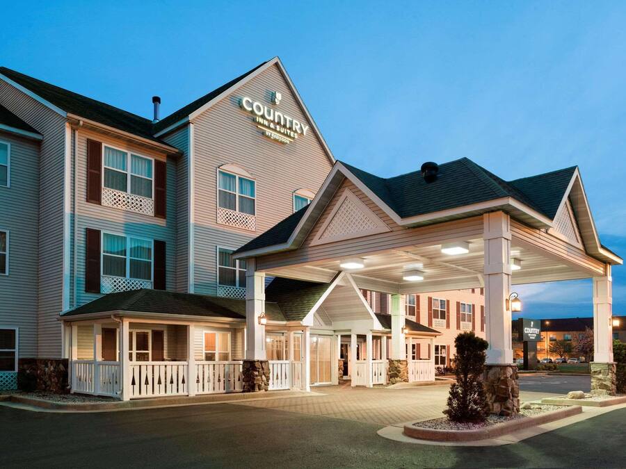 A Country Inn & Suites with a covered entrance, multiple windows, and a sign indicating it is by Budget Inn.