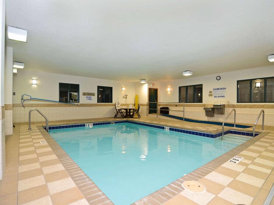 An indoor swimming pool with tiled walls, a clock, and signs indicating no diving.