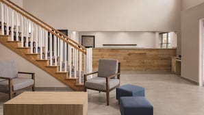 Un vaste espace de vie comprenant un escalier en bois, un coin salon avec une table et un comptoir de cuisine.