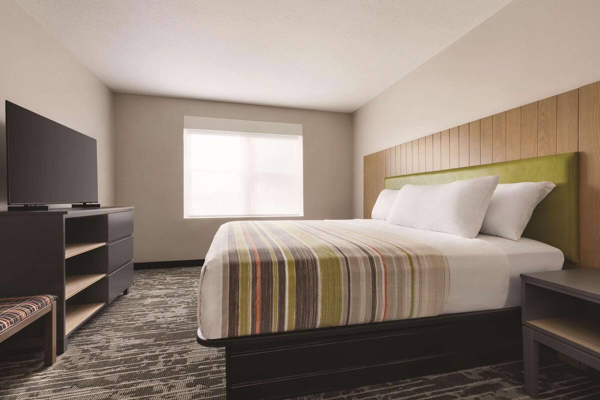 Une chambre d’hôtel avec un lit, une télévision, un bureau et une fenêtre.