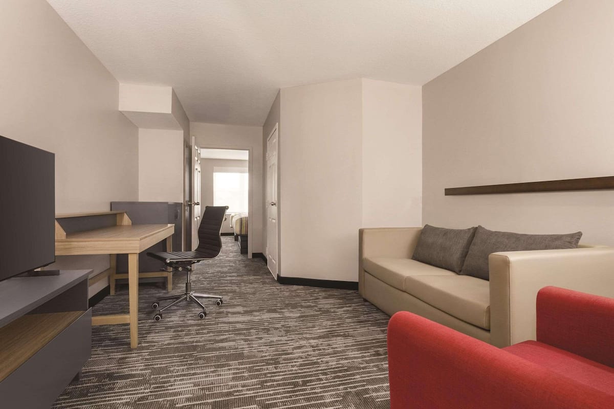 Une chambre d’hôtel équipée d’un bureau, d’une télévision, d’un canapé et d’un fauteuil rouge.