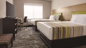 Une chambre d’hôtel avec deux lits, un bureau, une chaise et un téléviseur.
