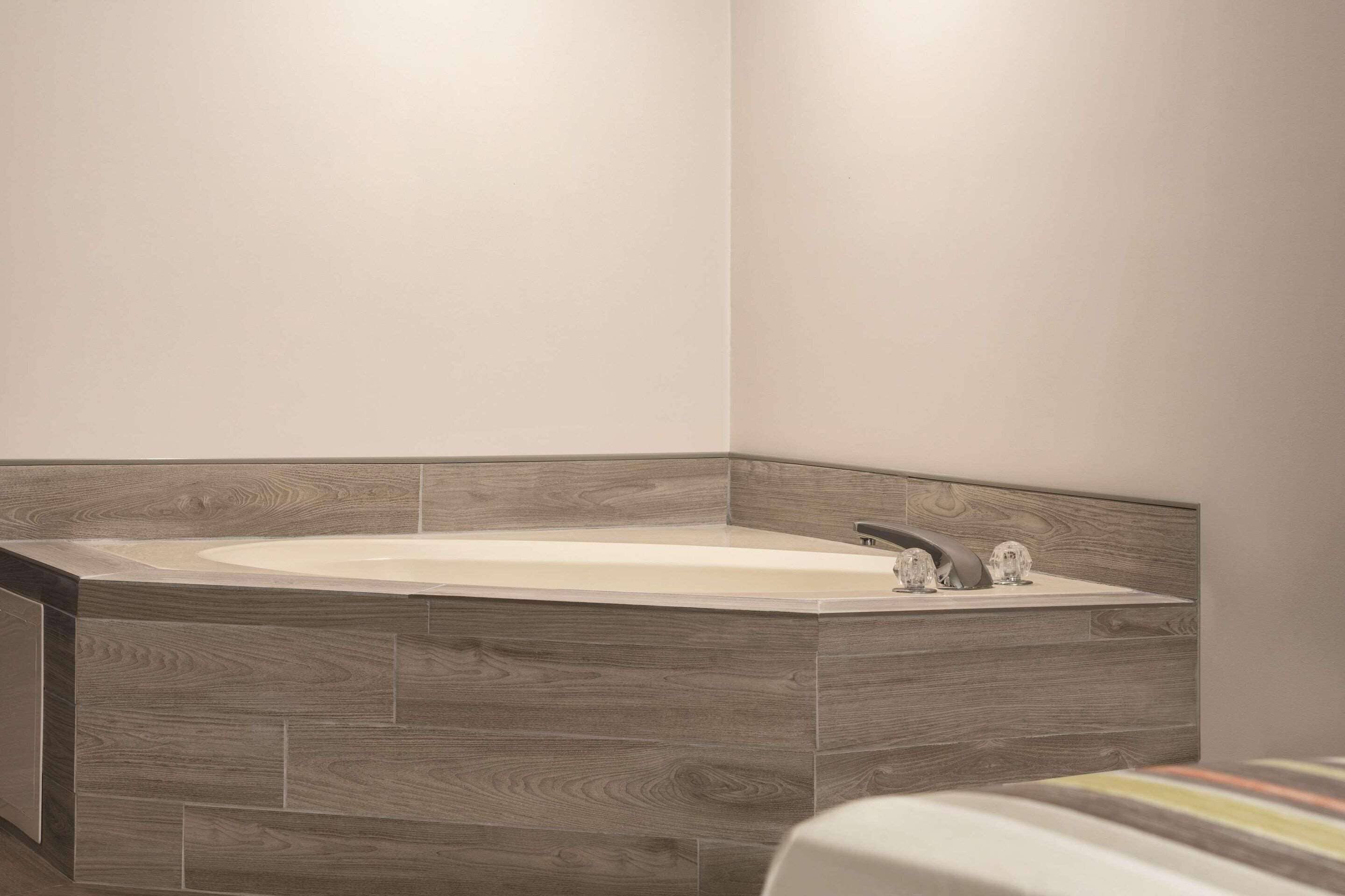 Un baño moderno con una bañera independiente, paneles de madera en la pared y una paleta de colores neutros.