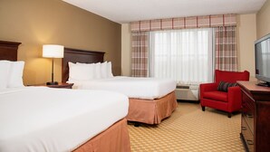 A hotel room with two beds, a red armchair, a television, and a window with curtains. - Country Inn & Suites by Radisson, Milwaukee West (Brookfield), WI (Brookfield)