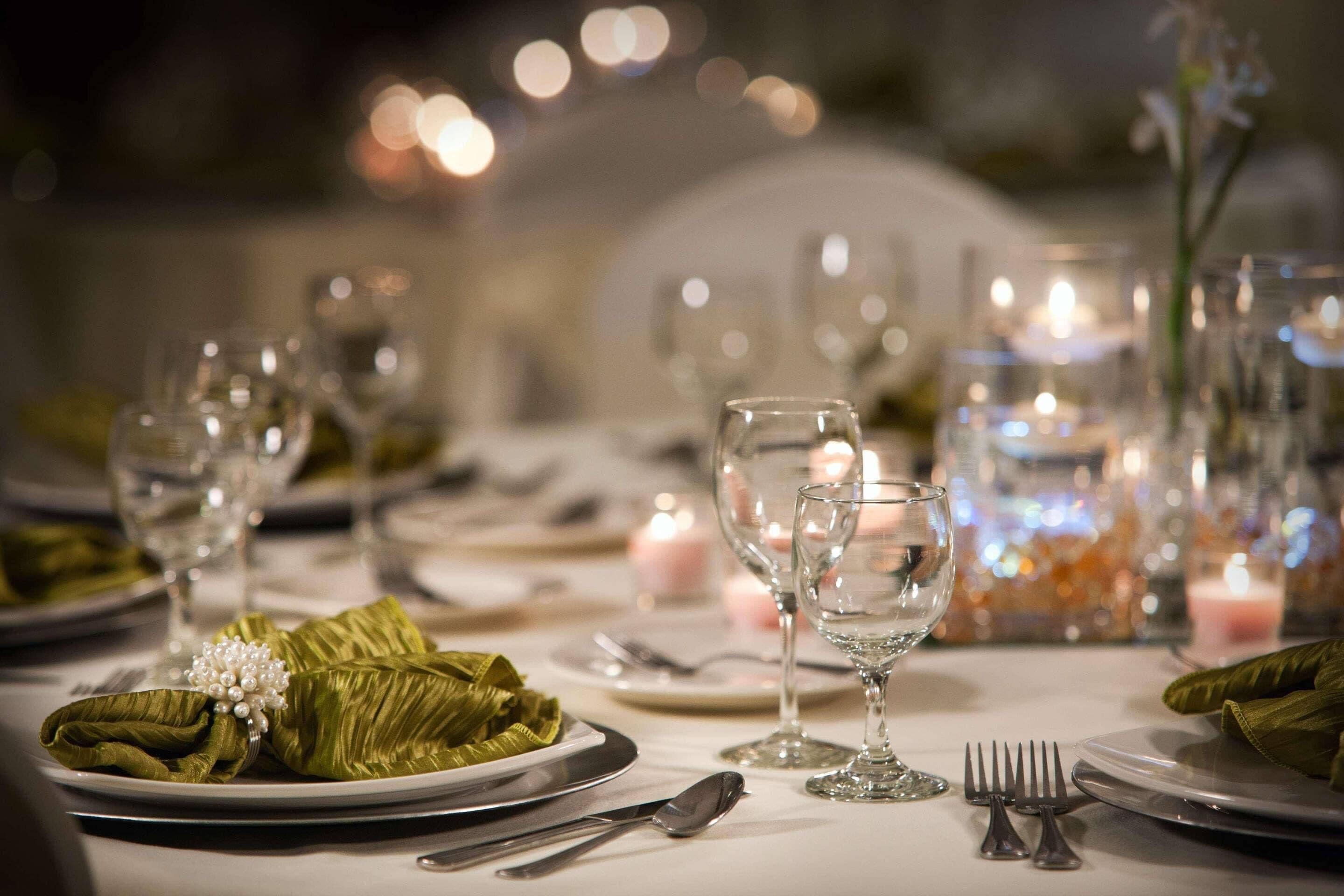 A table set for a formal dinner with clear glassware, plates, and silverware.