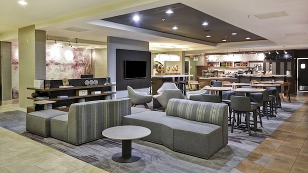A modern lounge area with sofas, a round table, and a bar with seating.