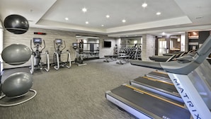A modern gym with treadmills, elliptical machines, and exercise balls.