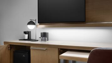 A modern office desk with a built-in monitor, a desk lamp, and a coffee machine.