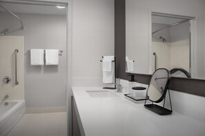 A modern bathroom with a bathtub, a sink, a mirror, and a shower area.
