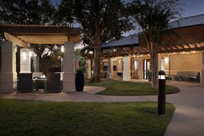 An outdoor patio area with seating, a pergola, and a fire feature.