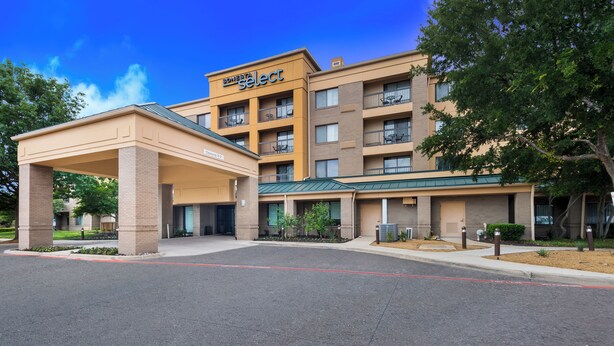 A hotel with a covered entrance, multiple balconies, and a sign reading "Select".
