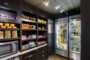 A self-service snack and beverage station with microwaves, refrigerators, and shelves stocked with snacks and drinks. - Sonesta Select Dallas Richardson (Richardson)