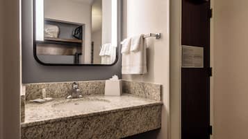 A bathroom with a granite countertop sink, a mirror, and a towel rack.