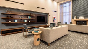 A modern hotel lobby with a seating area, a flat-screen TV, and a fireplace. - Sonesta Select Dallas Richardson (Richardson)