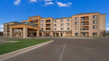 A hotel with multiple floors, a covered entrance, and a parking lot.