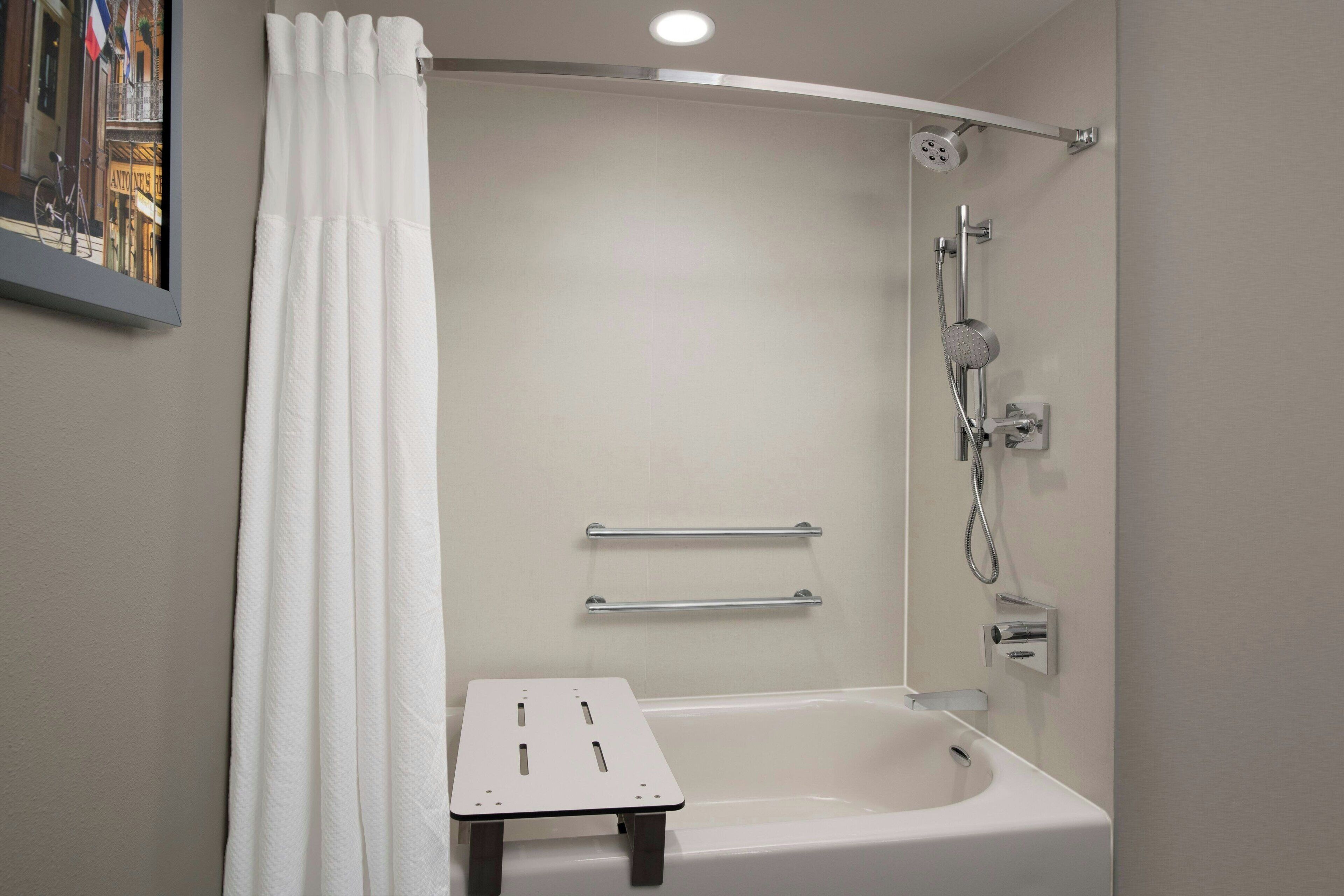 A modern bathroom with a bathtub, shower, and a small table.