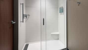 A glass-enclosed shower area with a white sink and a small shelf.