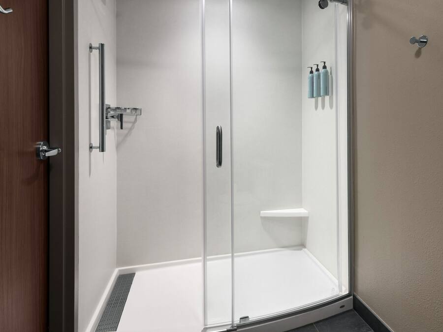 A glass-enclosed shower area with a white sink and a small shelf.