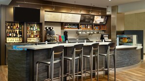 Zona de bar moderna con una barra curva, taburetes y una variedad de botellas de licor.