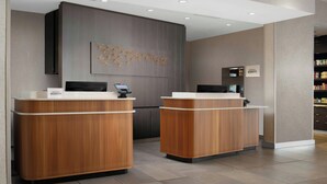 Una zona de recepción con dos mostradores de madera, una pared gris con una obra de arte decorativa y un letrero del hotel Marriott Bonvoy.