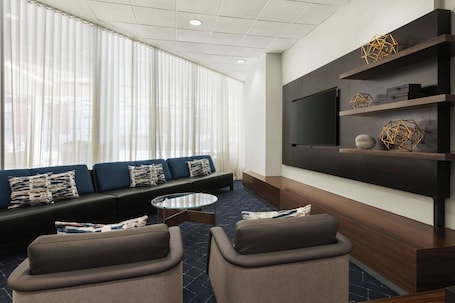 A modern living room with a sofa set, a coffee table, and a flat-screen TV mounted on a dark wooden wall.. Courtyard by Marriott San Francisco Fisherman's Wharf