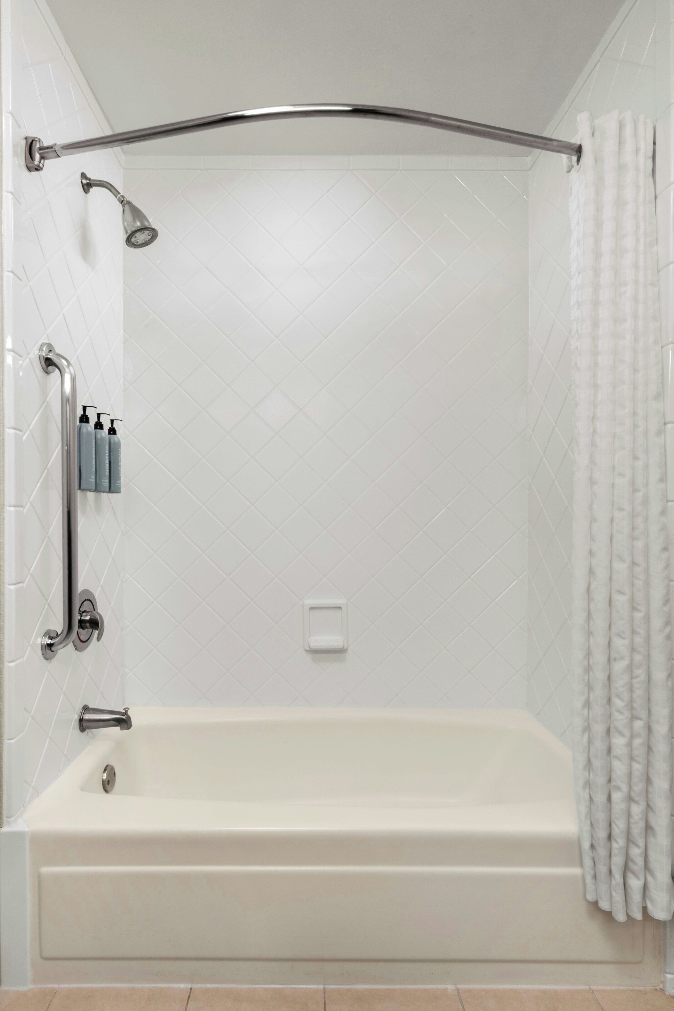 Ein modernes Badezimmer mit Badewanne, Dusche und Haltegriffen.