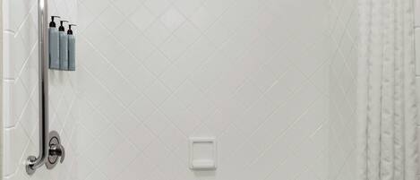 Ein modernes Badezimmer mit Badewanne, Dusche und Haltegriffen.